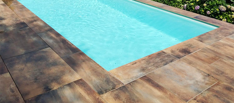 Vue d'ensemble de la terrasse et de la piscine après rénovation par Carrelage et Bain Junet à Lyon.