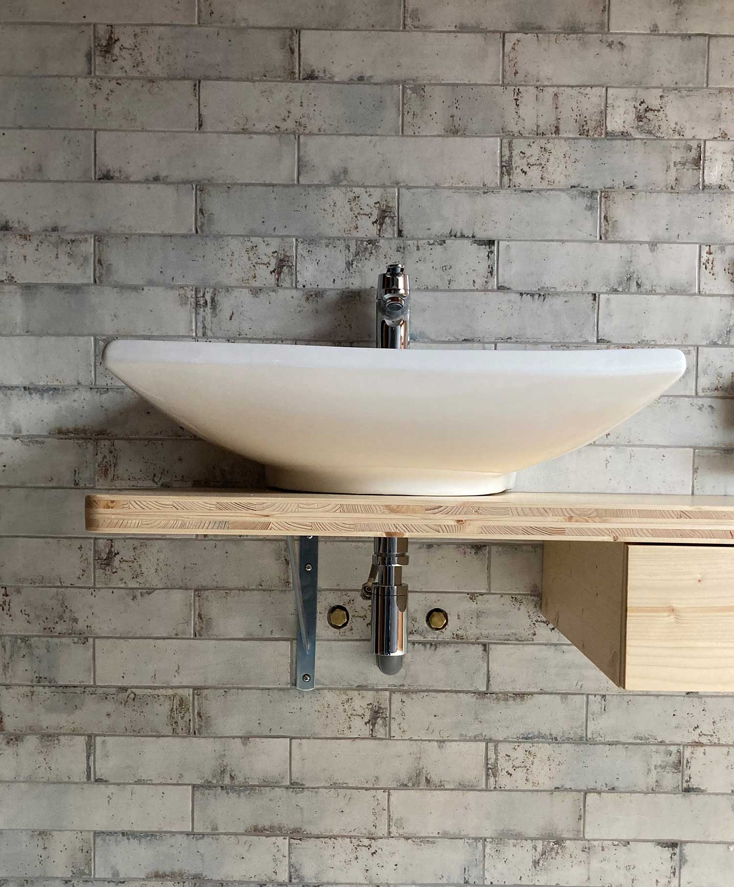 Salle de bain rénovée avec faïence effet brique coloris iron, projet réalisé par Le Carrelage Bugiste à Belley.